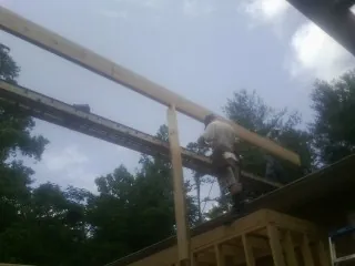 Carpenter setting a ridge beam over a new addition frame — Ice Dam Removal by Roofing Brothers in Henrieville