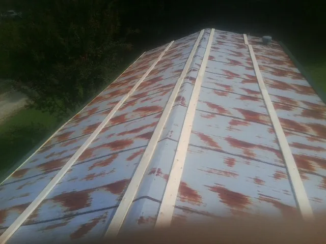 Rusted metal roof panels with new wood purlins before replacement — Storm Damage Roof Repair in Henrieville by Roofing Brothers