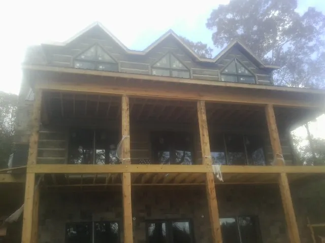 Dormers and porch framing on a large log home under construction — Roof Coating work by our crew in Henrieville