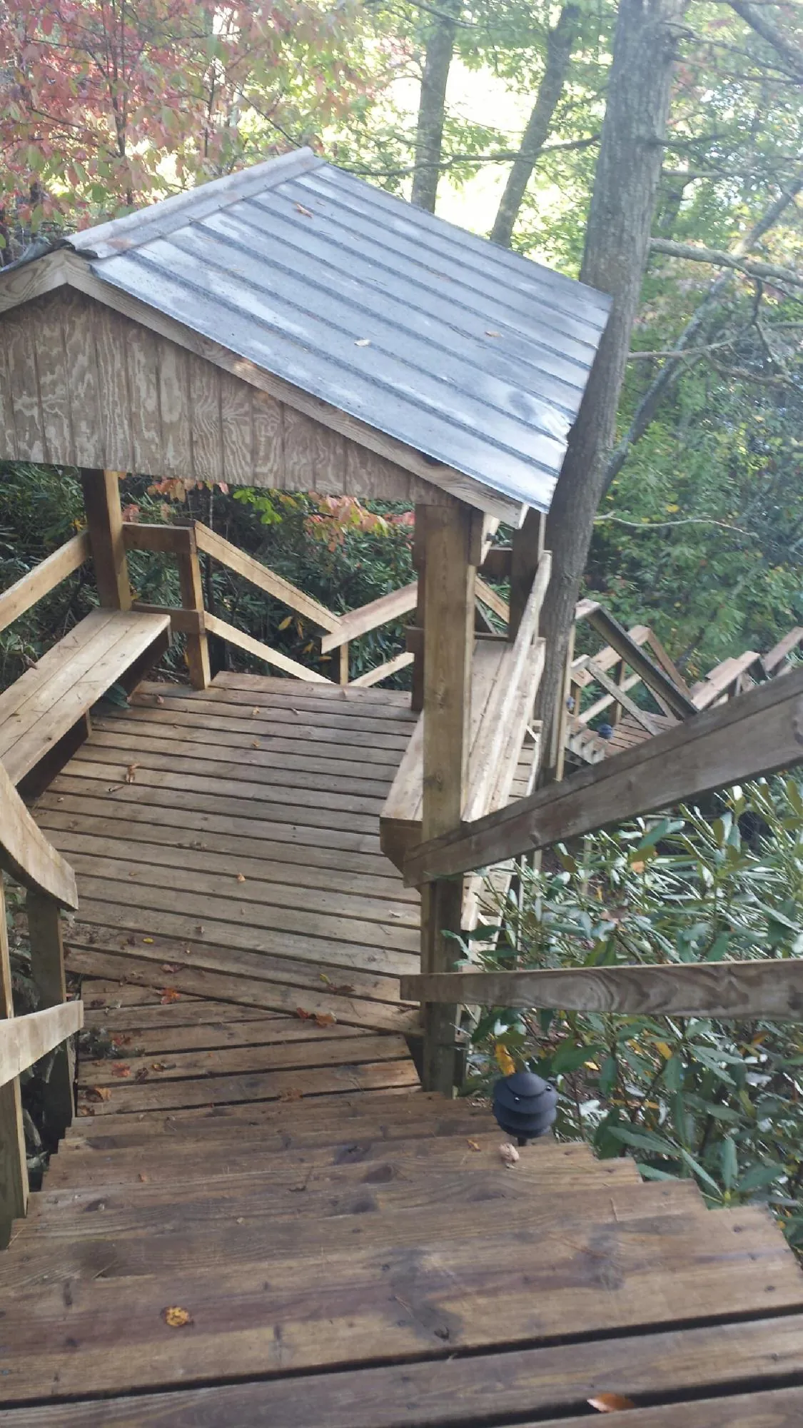 Metal roofed shelter over wooden steps on a wooded walkway — Skylight Repair & Installation work by our crew in Henrieville