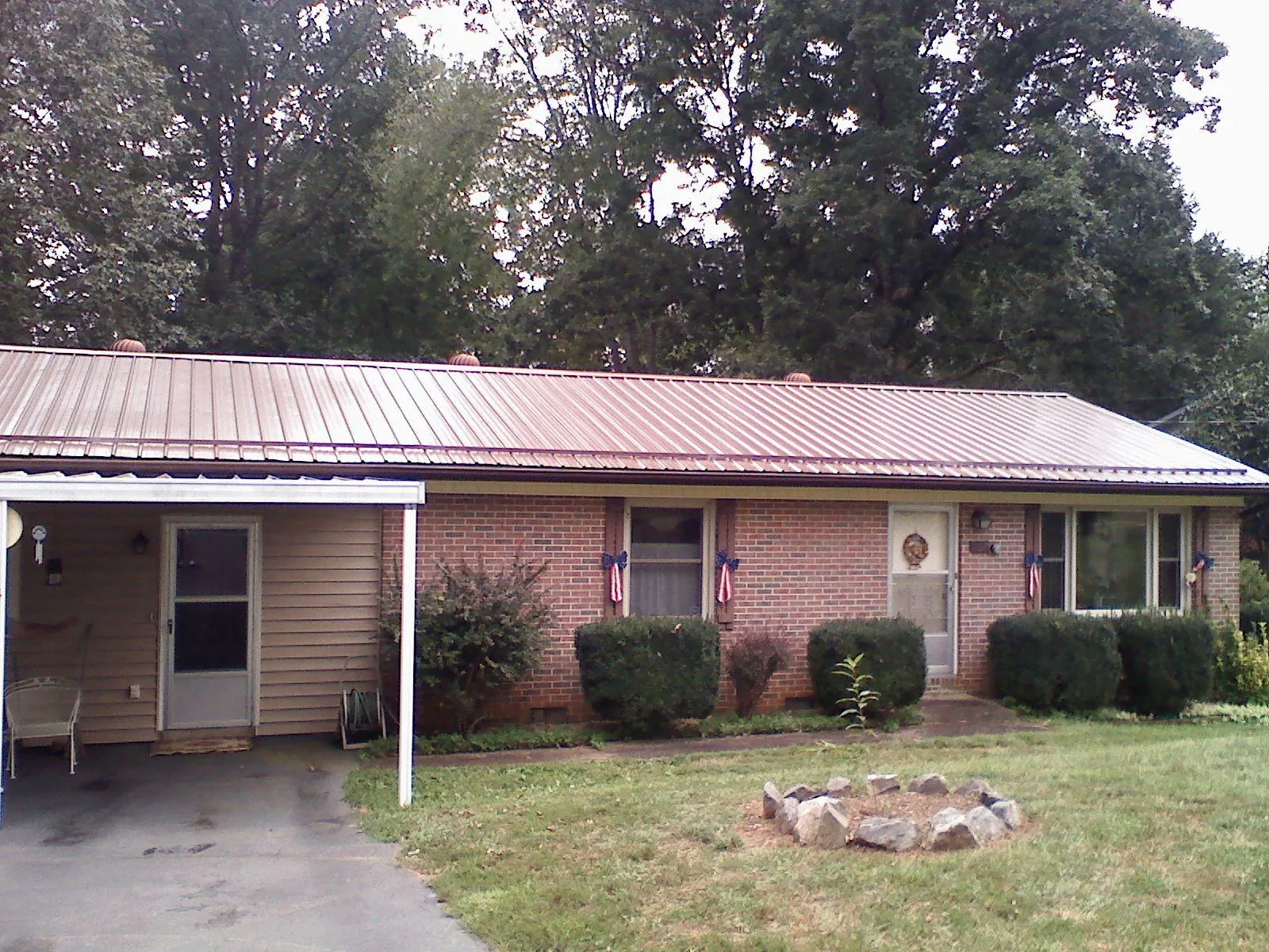 Bronze metal roof and carport on a brick ranch home — Roof Repair work by our crew in Henrieville