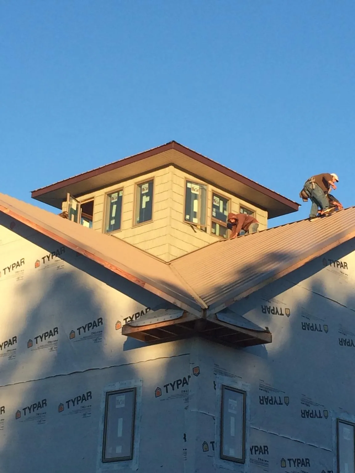 Roofers working around a rooftop cupola on a new metal roof at sunset — Roof Waterproofing in Henrieville by Roofing Brothers